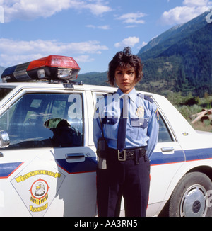 Policière tribale debout à côté de la voiture de police Lillooet, Colombie-Britannique, Canada Amérique du Nord juin 1990 KATHY DEWITT Banque D'Images