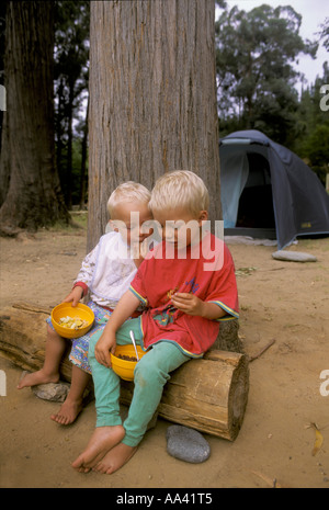 Petits garçons, deux et quatre ans, sont assis sur un journal pour manger du muesli, un terrain de camping en Afrique du Sud Banque D'Images