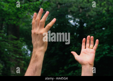 Une jeune de la mains atteignant l'homme de saisir quelque chose tendue Banque D'Images