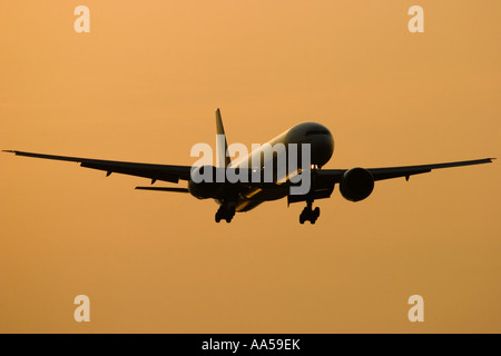 Silhouette d'un avion de ligne civil Boeing 777 à l'atterrissage à l'aéroport Heathrow de Londres, au coucher du soleil Banque D'Images