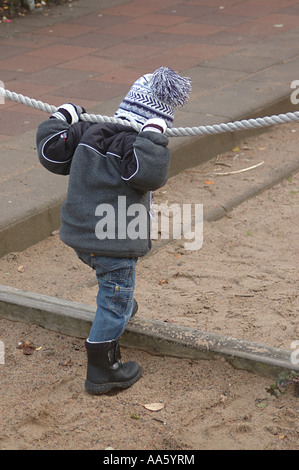 ANG104007 petit garçon de deux et demi ans debout tenant la corde dans les deux mains Banque D'Images