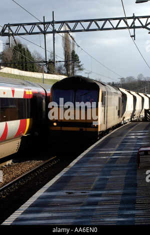 Freight train dans Crossflatts gare train de passagers à l'arrêt sur la ligne d'en face Banque D'Images