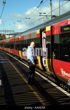 Commuter Train debout à Crossflatts station Guard sur la plate-forme contrôle de passagers de descendre Banque D'Images