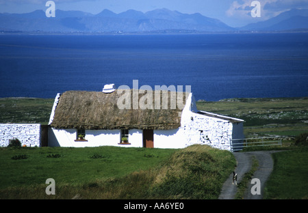 Cottage traditionnel blanchi à la chaume vu contre la mer et montagnes près de célèbre lieu de musique Dolin Co Clare Ireland Banque D'Images