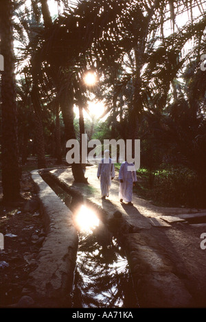 Oman Village d'Izki Men Walking si oasis créé par l'eau qui coule des montagnes grâce à un ancien système d'irrigation falaj Banque D'Images