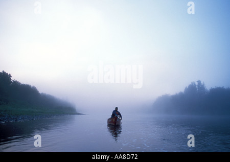 Un canot glisse à travers le brouillard et la brume d'un matin d'été sur la rivière Restigouche, dans le nord du Nouveau-Brunswick, Canada Banque D'Images