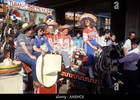 Les touristes américains poser pour photo avec âne peint comme un zèbre en vacances à Tijuana au Mexique Banque D'Images