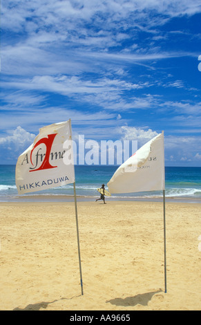 Surfer en marche à l'eau plage d'Hikkaduwa au Sri Lanka Banque D'Images