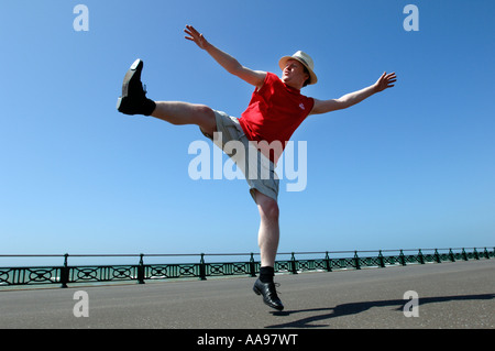 Un excès de middle-aged man doing maladroit kicking élevé danse de routine sur le front de mer de Brighton Banque D'Images