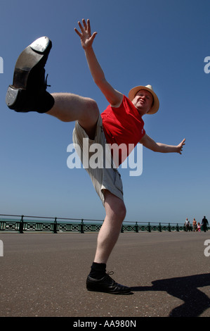 Un excès de middle-aged man doing maladroit kicking élevé danse de routine sur le front de mer de Brighton Banque D'Images