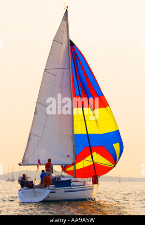 Trois hommes dans un bateau. La voile au crépuscule. Le port de Poole, Dorset. UK Banque D'Images