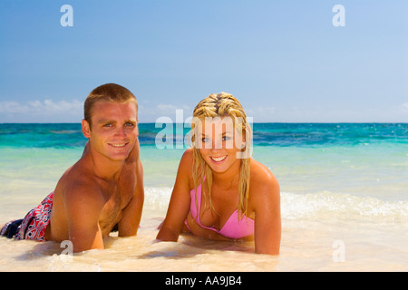 Jeune couple allongé sur le sable au bord de l'eau Banque D'Images