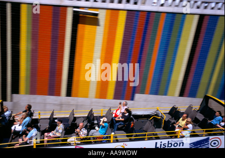 Open top bus touristique roulant sur une route en face d'un mur à rayures de couleurs vives Banque D'Images