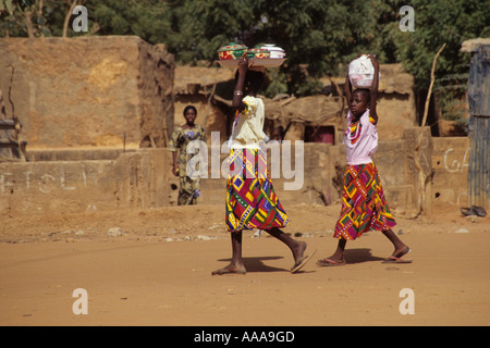 Niamey, Niger, Afrique de l'Ouest. Les filles transportant de la nourriture dans des bols sur la tête d'un voisin Banque D'Images