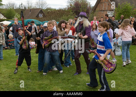 Les enfants jouent avec la guitare guitares jouet en caoutchouc gonflable. Glam rock band le look. South Stoke, Berkshire, le 1er mai foire de village Banque D'Images