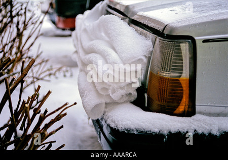 La décongélation snow glisse lentement le capot d'une voiture et fait des plis soignée sur le bouclier Banque D'Images