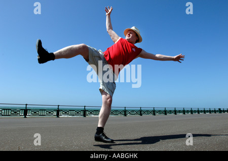 Un homme d'âge moyen surpoids maladroit de faire des coups de danse de routine sur le front de mer de Brighton Banque D'Images