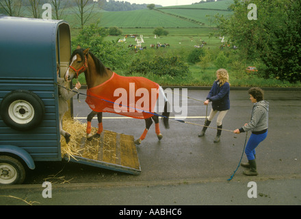 Adolescente et mère aident à obtenir leur cheval dans la remorque - la boîte à chevaux 1980s après un événement local Pony Club Gymkhana. HOMER SYKES Banque D'Images