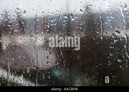 Vue sur un jardin & maisons prises par le biais d'une fenêtre tachés de pluie Banque D'Images