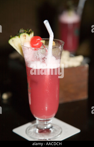 Cocktail Singapore Sling avec de la paille et de cerise dans le verre sur la table à l'Hôtel Raffles Long Bar de Nuit Banque D'Images