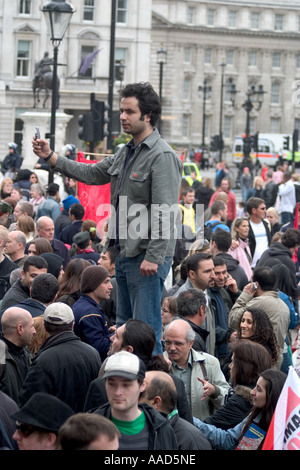 Homme debout au-dessus de foule prendre photo sur téléphone mobile pendant manifestation du Mayday. Trafalgar Square, Londres, Angleterre Banque D'Images