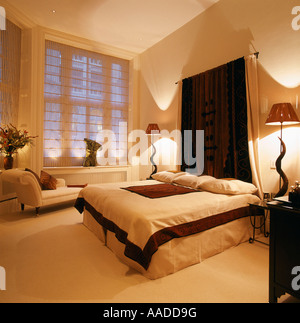 Tête de lit en tissu accroché au-dessus du divan dans la chambre avec des lampes et chaise longue fenêtre ci-dessous Banque D'Images
