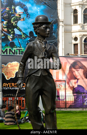 Black bronze statue de Charlie Chaplin contre film coloré des panneaux dans Leicester Square, London, England, UK Banque D'Images