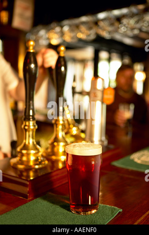 La bière anglaise sur pub bar haut à côté de pompes à main Banque D'Images