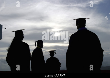 Quatre jeunes diplômés trois hommes et une femme amis portant une robe de graduation Banque D'Images