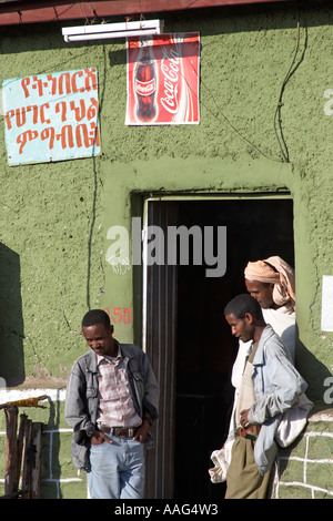 Hommes debout à l'extérieur de l'atelier avec Coca Cola signes dans village de Dejen près de Shafartak Afrique Ethiopie pont Banque D'Images