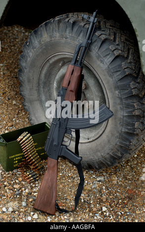 Kalashnikov AK47 avec boîte de munitions et une ceinture de balles appuyé contre une roue de land rover Banque D'Images