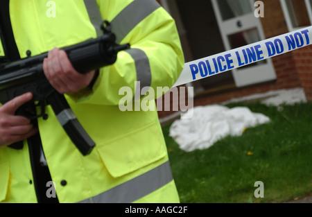 Un officier de police dans une veste réfléchissante tenant un Heckler et Koch MP5 machine gun à un crimescene Banque D'Images