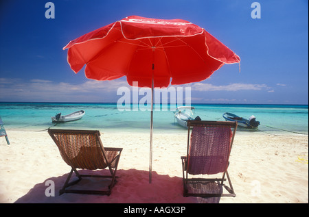 Mexique Playa del Carmen deux chaises de plage vide sous un parapluie rouge face à l'océan Banque D'Images