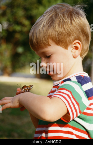 Pre-k Garçon 23 ans jouer avec papillon sur bras à la crainte et l'émerveillement avec nature beauté nature belle copie espace libre POV Banque D'Images