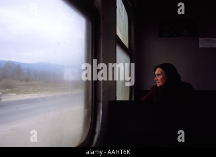 Foulard femme regarde par la fenêtre de d'un coach, voie étroite Septemvri-Dobrinishte train line, Bulgarie Banque D'Images