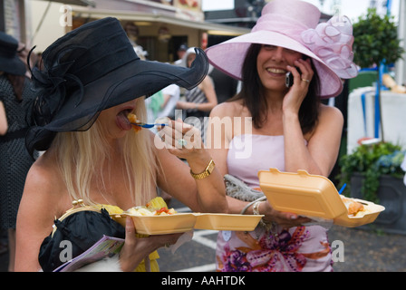 Manger Fish n Chips deux jeunes femmes, femme sur un téléphone portable, manger parlant en même temps. Derby Day Epsom Downs, Surrey, Angleterre des années 2007 2000 Royaume-Uni Banque D'Images