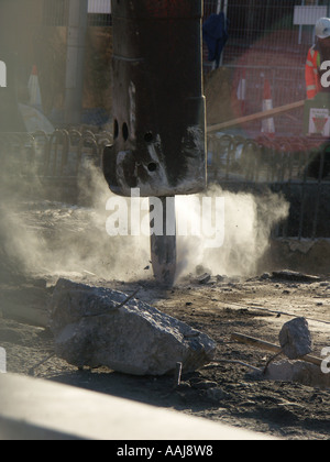 Briser la surface en béton avec un marteau pneumatique. Beaucoup de poussière par le soleil en contre-jour. Banque D'Images
