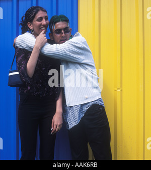 Jeunes asiatiques avec le Pakistan une écharpe, les cheveux teint en vert et Moschino shirt avec amie devant un mur de couleur. Banque D'Images