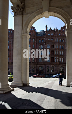 Figure la marche loin de Manchester Central Library avec le Midland Hôtel vu par le portique Banque D'Images