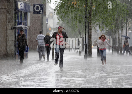 Deux enfants pris dans une tempête de pluie couler le long de la rue principale de Bromsgrove dans Worcestershire UK Banque D'Images