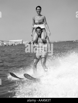 1960 SKI Femme avec de l'EAU L'HOMME EN MAILLOT À CHEVAL SUR LES ÉPAULES Banque D'Images