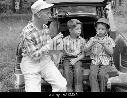 Années 1950 Années 1960 Père deux jeunes fils avec des cannes à pêche EN VOITURE PISCINE Banque D'Images