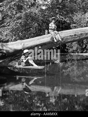 Années 1940 Années 1950 Paire de garçons dans les chapeaux de paille et menotté en pêche au large flux JEANS D'ARBRE TOMBÉ AVEC STICK & STRING POLONAIS Banque D'Images