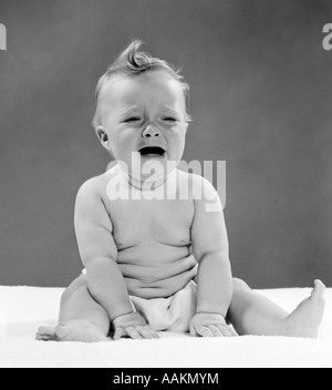 1950 bébé qui pleure assis avec DISTRESSED EXPRESSION & LARMES DANS LES YEUX Banque D'Images