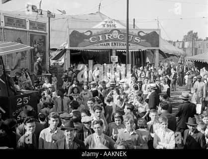 1940 FOULE DE PERSONNES HOMMES FEMMES ENFANTS L'ÉVICTION À mi-chemin à l'EXTÉRIEUR DE L'ENTRÉE PRINCIPALE DE L'BIG TOP TENTE DE CIRQUE Banque D'Images