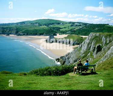 Couple assis sur un banc sur les falaises de Pennard, en regardant la vue de Three Cliffs Bay, Gower Peninsula, au sud du pays de Galles. Banque D'Images