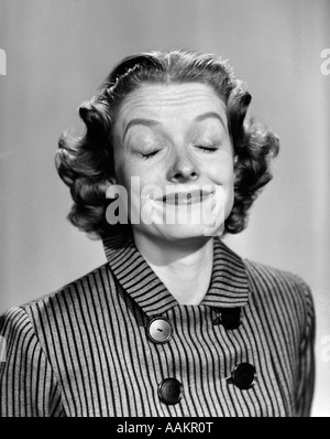 Années 1950 Années 1960 YOUNG WOMAN SMILING EYES CLOSED FAIRE UNE Drôle de tronche en robe rayée AVEC DES BOUTONS Banque D'Images