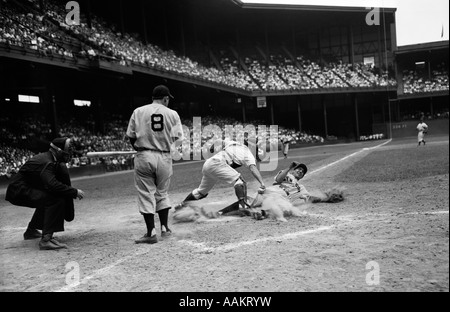 Années 1950 et juge-arbitre d'un match de baseball BATTER REGARDEZ COMME CATCHER PROTÈGE LA PLAQUE TOUT EN RUNNER COULISSE DANS ESSAYANT DE VOLER HOME Banque D'Images