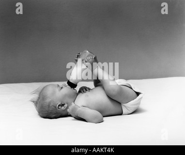 1940 sujets bébé boire À PARTIR DE BOUTEILLE DE LAIT QUI A EU LIEU AVEC LES PIEDS Banque D'Images