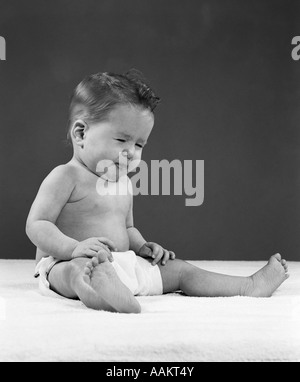 Années 1950, la FIGURE COMPLÈTE BÉBÉ ASSIS PORTANT DES COUCHES FUNNY FACE Banque D'Images